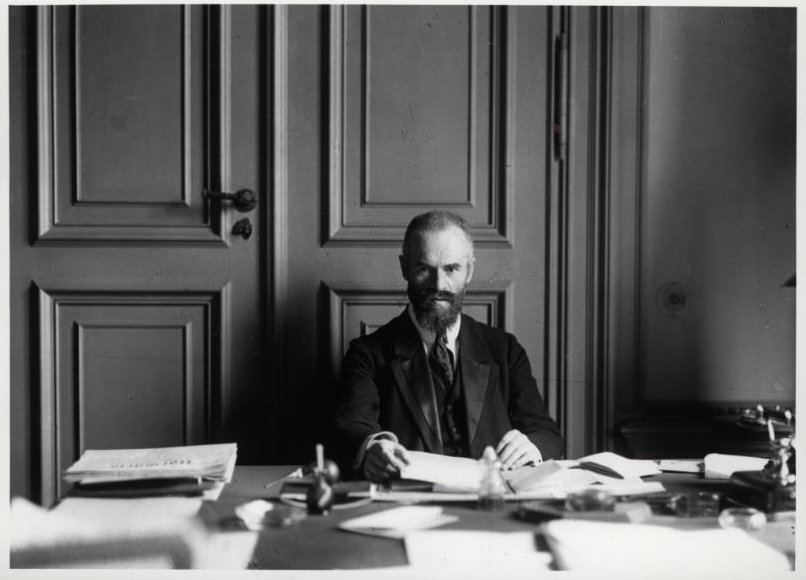 Otto Landsberg, an seinem Schreibtisch voller Akten sitzend.